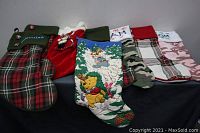 Photo showing six stockings with different patterns including plaid, velvet, Disney character Pooh, and camouflage designs, highlighting variety in the lot.