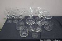 Collection of 15 assorted fancy drinking glasses arranged on a dark surface, showcasing different styles including martini and cocktail glasses.