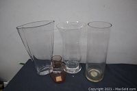 All four vases together: three larger clear glass vases in varied shapes and one small amber glass vase.