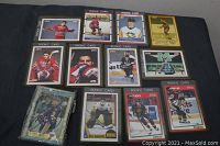 Overview of 12 vintage looking hockey rookie cards laid out on black surface. Cards mainly from Score series, early 90s.
