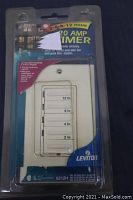 Leviton branded 20 amp dimmer switch in original plastic packaging, showing slider one the front with timer settings for 2, 4, 8, and 12 hours.