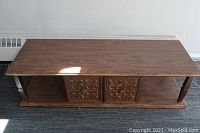 Photo showing the full top view of the wooden coffee table with visible carved doors on the lower shelf.