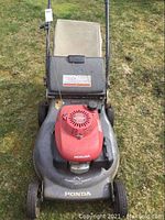 Front full view of the Honda lawnmower showing grass catcher bag, handle, and deck with Honda branding.