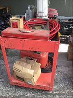 Full side-on view of the red metal trolley with items stored on it (not included). Shows overall condition and structure.