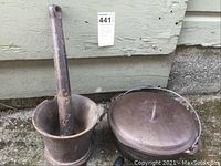 Photo showing the cast iron mortar and pestle next to the cast iron Dutch oven with lid on the ground.