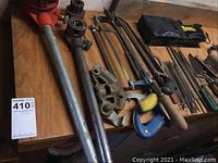 Workbench surface displaying ratchet pipe threader, extension bars, die heads, pipe vise and hacksaw frames