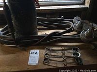 Black acetylene tank with orange hoses and pressure regulators, metal hose clamps on wooden surface.