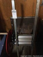 Front view of manual grape crusher showing frame and red flywheel