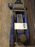 Top-down view of blue hydraulic floor car jack with label showing 2-ton capacity and handle slot.