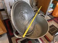 Photo showing a large aluminum container with a lid and measuring tape stretched across its diameter, displaying roughly 18 inches.