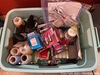 Overview of painting supplies, electrical outlets, light bulbs, and cables packed inside a blue plastic tub.