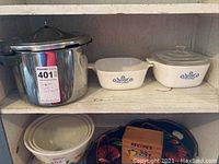 Photo showing stainless steel Presto pressure cooker with lid, two white Corningware casseroles with blue floral pattern, one with lid, one without