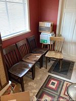 Four wooden dining chairs arranged in a row, three dark brown and one lighter wood, showing overall worn finish.