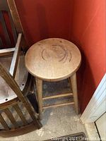 Wooden round stool with visible wear and some marks on seat
