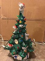 Full view of ceramic Christmas tree decorated with colorful bulbs and mice wearing Santa hats
