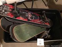 Plastic bin containing stacked skateboard decks and parts