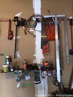 Wall mounted hand tools including pipe wrench, quick grip clamp, saw, metal square, and rulers