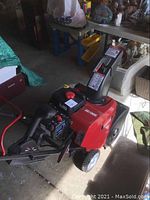 Full view of red snowblower showing chassis, wheels, engine and handlebar assembly