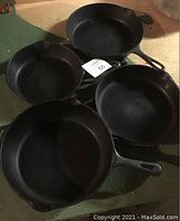 Top view of four cast iron pans showing various sizes and shapes of pans grouped together on a green surface