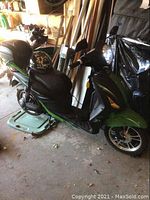 Left side view of green and black e-bike showing seat and helmet on rack