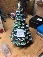 Front view of the 20-inch tall green ceramic Christmas tree decorated with multicoloured bulb inserts and white frosting on branches.