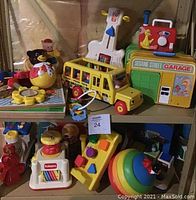 Shelf displaying various vintage toddler toys including Sesame Street, Playskool, Fisher Price, Disney items.