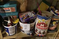 Four assorted containers including LEGO bricks, Tinkertoy set, and army men figures on a wooden shelf