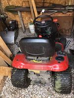 Rear view of red Craftsman lawn tractor showing black vinyl seat, steering wheel and dual rear wheels.
