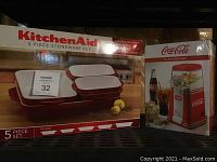 Photo of boxed KitchenAid 5-piece stoneware set and Coca-Cola hot air popcorn maker boxes together.
