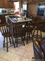 Four dark wooden swivel barstools in a kitchen setting near an island counter.