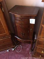 Front angle view of entire jewelry cabinet standing on carpet with power cord at base
