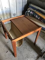 Full view of the teak magazine table showing rectangular top, frame and cloth sling.