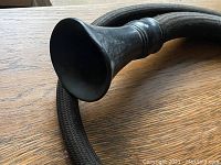 Close-up of the wide bell-shaped metal funnel end of the conversation tube on a wooden surface
