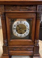 Front view of carved wood case with brass dial and beveled glass