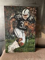 Front view of the oil painting showing football player running with ball in black and white uniform.