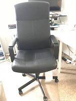 Front view of black Ikea swivel office chair showing padded seat, backrest, and armrests with caster wheel base.