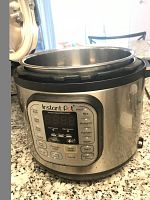 Side view of Instant Pot Duo pressure cooker with digital control panel and open lid showing inner pot.