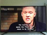 Front view of Samsung 50 inch TV powered on showing image with subtitles.