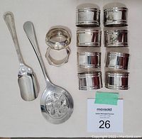 Photo showing 8 matching plain silverplate napkin rings, two additional matching napkin rings, and two silverplate serving spoons (one slotted).