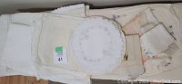 Top view of assorted folded vintage linens including handkerchiefs, doilies, tablecloths with lace and embroidered details
