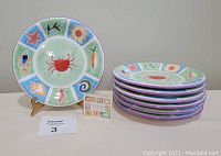 Set of 7 Enesco 1999 nautical themed plates stacked with one plate displayed upright on a stand with a description card
