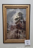 Framed J W Gozzard print showing a village scene with figures and horses on a road under a cloudy sky. The frame is an ornate gold textured border.