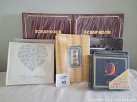 Photo showing 2 burgundy scrapbooks, a beige digital photo album, 2 white photo albums with heart design, 2 yellow photo albums, and 2 blue photo albums with celestial motifs.