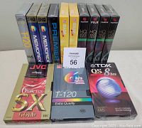 Front view of all 13 new, sealed VHS tapes showing various brands and packaging styles, including Hi-Tec, Memorex, BASF, FujiFilm, JVC, TDK, Premier's Choice, and BASK.