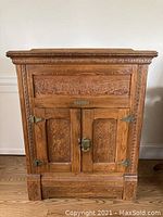 Front view showing carved panels and brass hardware