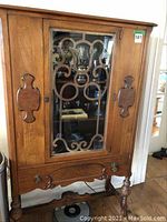 Full view of antique wooden china cabinet with glass door and decorative wooden scrollwork