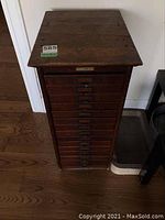 Full frontal view of tall wooden cabinet with all drawers closed
