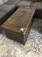 Trunk closed showing carved lid and side floral scrollwork