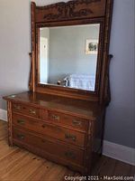 Full front view of carved wooden dresser with attached large mirror showing ornate carvings and brass hardware.