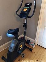 Full view of exercise bike with included weights and DVDs on floor